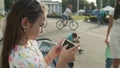 Serious girl playing on mobile phone in park. Cute girl using phone outside