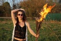 Serious girl in sunglasses standing in a black jacket with a fire in his hands Outdoors