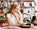 Serious girl typing on notebook in library Royalty Free Stock Photo