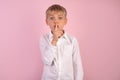 Serious good looking young boy with trendy hairdo, keep fore finger on lips, tries to keep conspiracy, looks aside, says: Sh, make Royalty Free Stock Photo