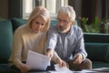 Serious grey haired mature couple calculating bills, checking finances together Royalty Free Stock Photo