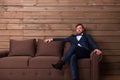 Serious groom in suit and bow-tie sitting on couch Royalty Free Stock Photo