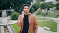 Serious guy calling phone at park closeup. Focused man talking telephone waiting Royalty Free Stock Photo