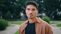 Serious guy posing park portrait. Young man face looking camera standing nature Royalty Free Stock Photo