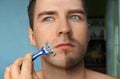 Serious guy shaving his beard