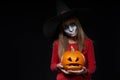 Serious Halloween witch holding Jack O`Lantern pumpkin looking at camera