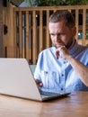 Serious handsome arabian man with beard is using laptop, reading email, typing on keyboard in cafe. Royalty Free Stock Photo