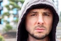 Serious handsome bearded man in a hood against a blurred background, closeup portrait