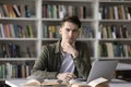 Serious handsome college student writing essay in university library Royalty Free Stock Photo