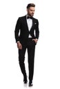 Serious handsome man in tuxedo walks and looks to side