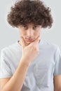 Serious and handsome a young man with curly hair he looks into the camera with his blue eyes, his hands on his face, a portrait of Royalty Free Stock Photo