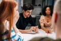 Serious handsome young man playing fun cards games telling associations to diverse friends, enjoying pastime activity Royalty Free Stock Photo