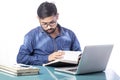 Serious hard working man wearing eyeglass reading diary while working on computer Royalty Free Stock Photo