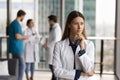 Serious head doctor woman standing in hospital hall space