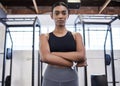 Serious about her fitness. Portrait of a sporty young woman standing with her arms crossed in a gym. Royalty Free Stock Photo