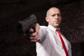 Serious hired murderer in red tie aims a gun Royalty Free Stock Photo