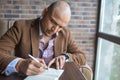Serious indian man making some notes in his notebook, business plan or diary writing. Royalty Free Stock Photo