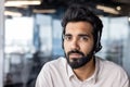 Serious Indian man wearing a headset works in the office and looks confidently at the camera, close-up portrait Royalty Free Stock Photo