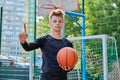 Serious kid teenager with basketball ball showing thumb up attention sign hand gesture Royalty Free Stock Photo