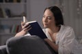 Serious lady reads a book in the night at home