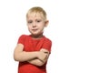 Serious little blond boy in a red t-shirt stands with folded arms. Isolate on white background Royalty Free Stock Photo