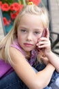 Serious little blond girl talking on a cellphone