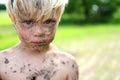 Serious Little Boy Covered in Dirt and Mud Outside