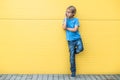 Serious little boy talking on cell phone standing near yellow wall outdoors Royalty Free Stock Photo