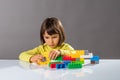 Serious little child playing with building bricks with engineer imagination