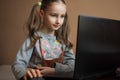 Serious little girl is concentrated in front of her black laptop while focused on doing homework during the quarantine Royalty Free Stock Photo