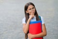 Serious little kid in glasses hold school books with thoughtful look outdoors, imagination Royalty Free Stock Photo