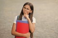 Serious little kid in glasses hold school books with thoughtful look outdoors, imagination Royalty Free Stock Photo