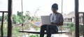 A serious looking Asian man is working hard using his laptop computer. sitting on a wooden swing Royalty Free Stock Photo