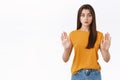 Serious-looking confident good-looking woman in yellow t-shirt, raising hands in stop, taboo or prohibition motion, look