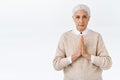 Serious-looking determined and patient old woman, senior lady with grey combed hair, press palms together over chest in Royalty Free Stock Photo