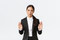 Serious-looking displeased asian female manager, businesswoman in black suit stop action, prohibit or restrict something