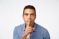 Serious-looking young hispanic man bending towards camera, shushing, make shush or shh sound as press finger to lips Royalty Free Stock Photo