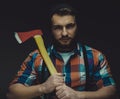 Serious lumberjack. Confident young bearded man holding a big axe