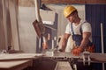 Serious male builder using woodworking machine in workshop Royalty Free Stock Photo