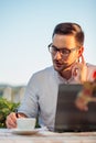 Serious male businessman using laptop and writing down notes, working in a restaurant Royalty Free Stock Photo