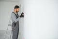 Serious male electrician installing power socket in the apartment and using screwdriver Royalty Free Stock Photo