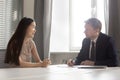Serious hr employer listening to asian applicant at job interview