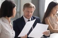 Serious team leader reviewing financial report with asian female coworker. Royalty Free Stock Photo