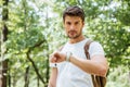 Serious man with backpack checking time and looking at watch Royalty Free Stock Photo