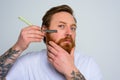 Serious man with blade is focused on cutting his beard