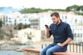 Serious man checking phone on a ledge on vacation
