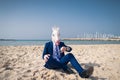 Serious man in comical mask sits on the sand and enjoys sunny day