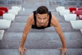 Serious man doing pushups on stadium stairs