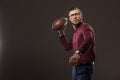 serious man in eyeglasses throwing rugby ball and looking at camera