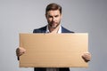 Serious man holds the sign, blank card. Placard ready for your product. Sign to your text. Handsome man showing blank